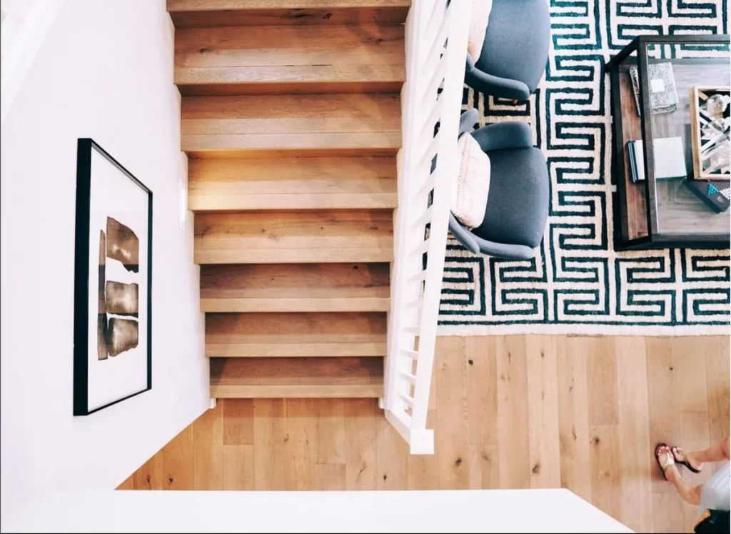 Blick ins moderne Wohnzimmer mit Holztreppe – Symbol für steigende Immobilienpreise bei Zinsanstieg